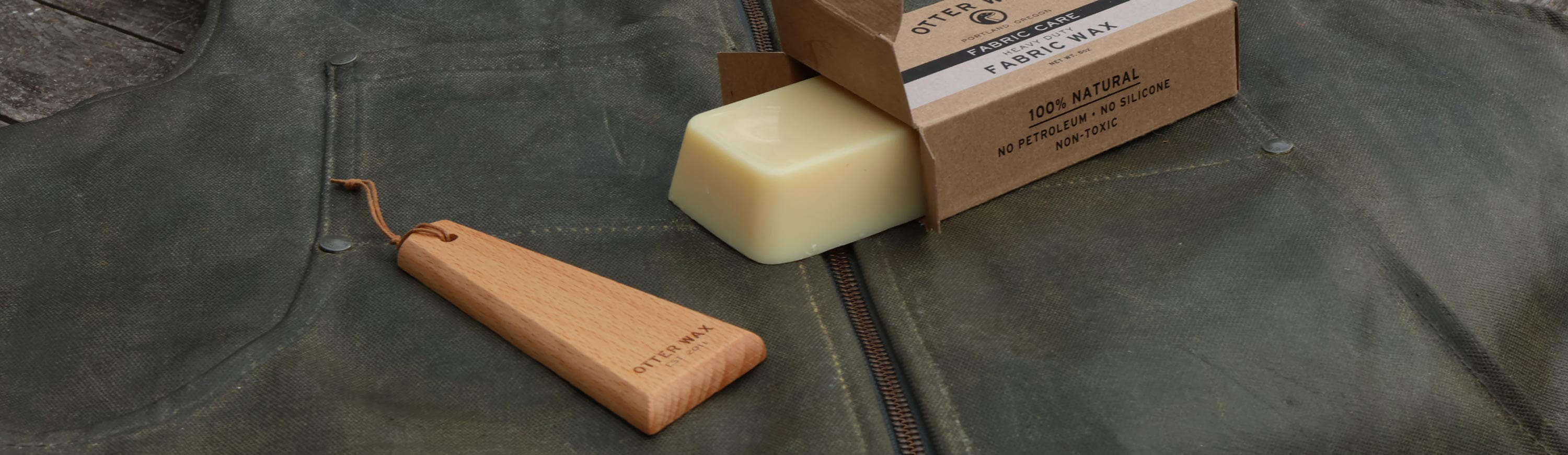 A bar of otter wax and a smoothing tool on waxed canvas