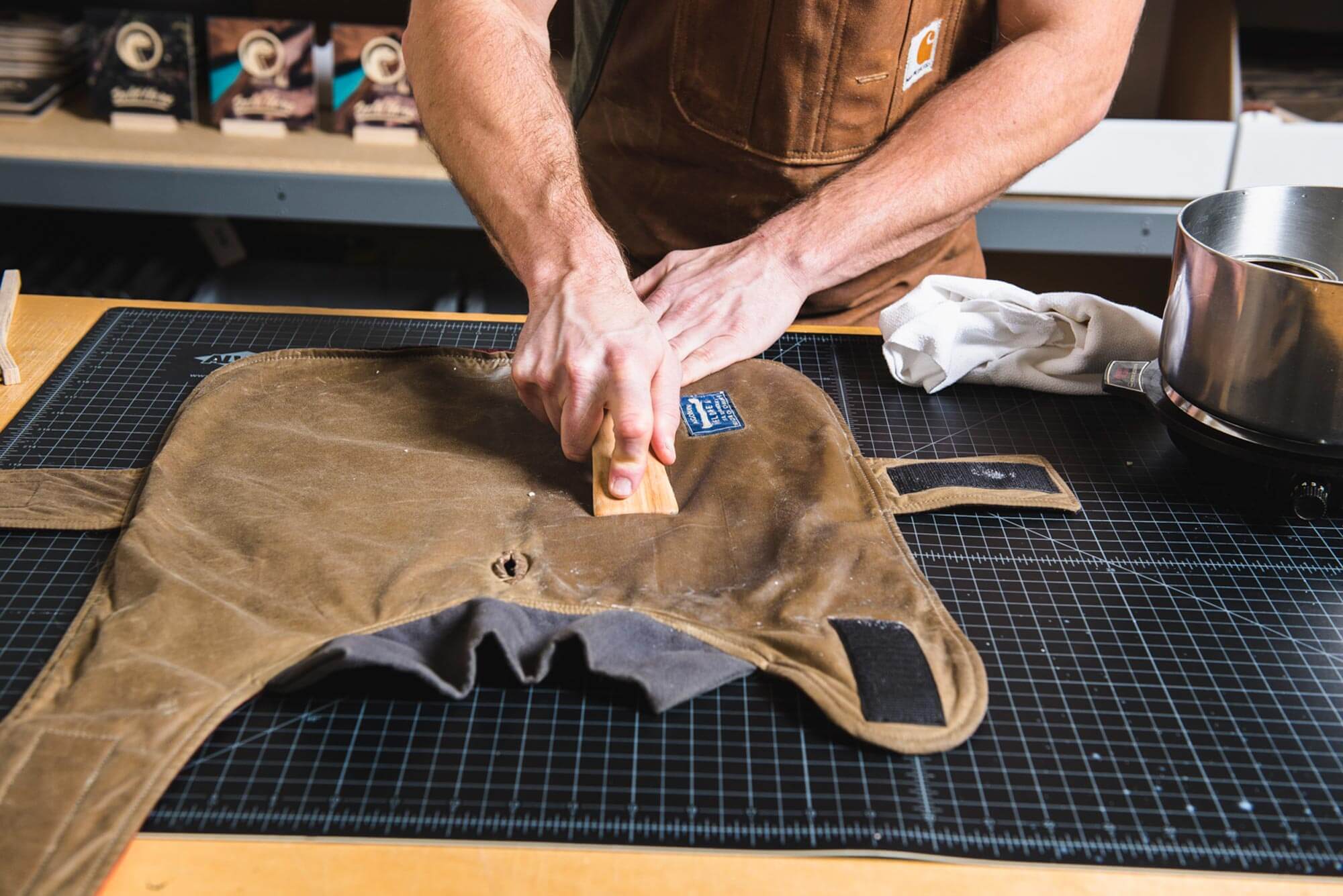 hands using a wood smoothing tool to press wax into waxed canvas