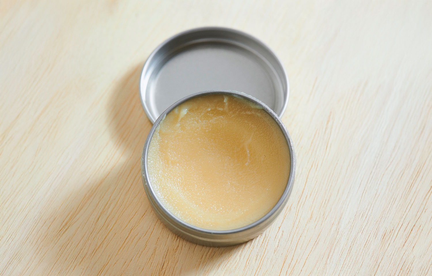 open tin of otter wax leather salve on wood surface