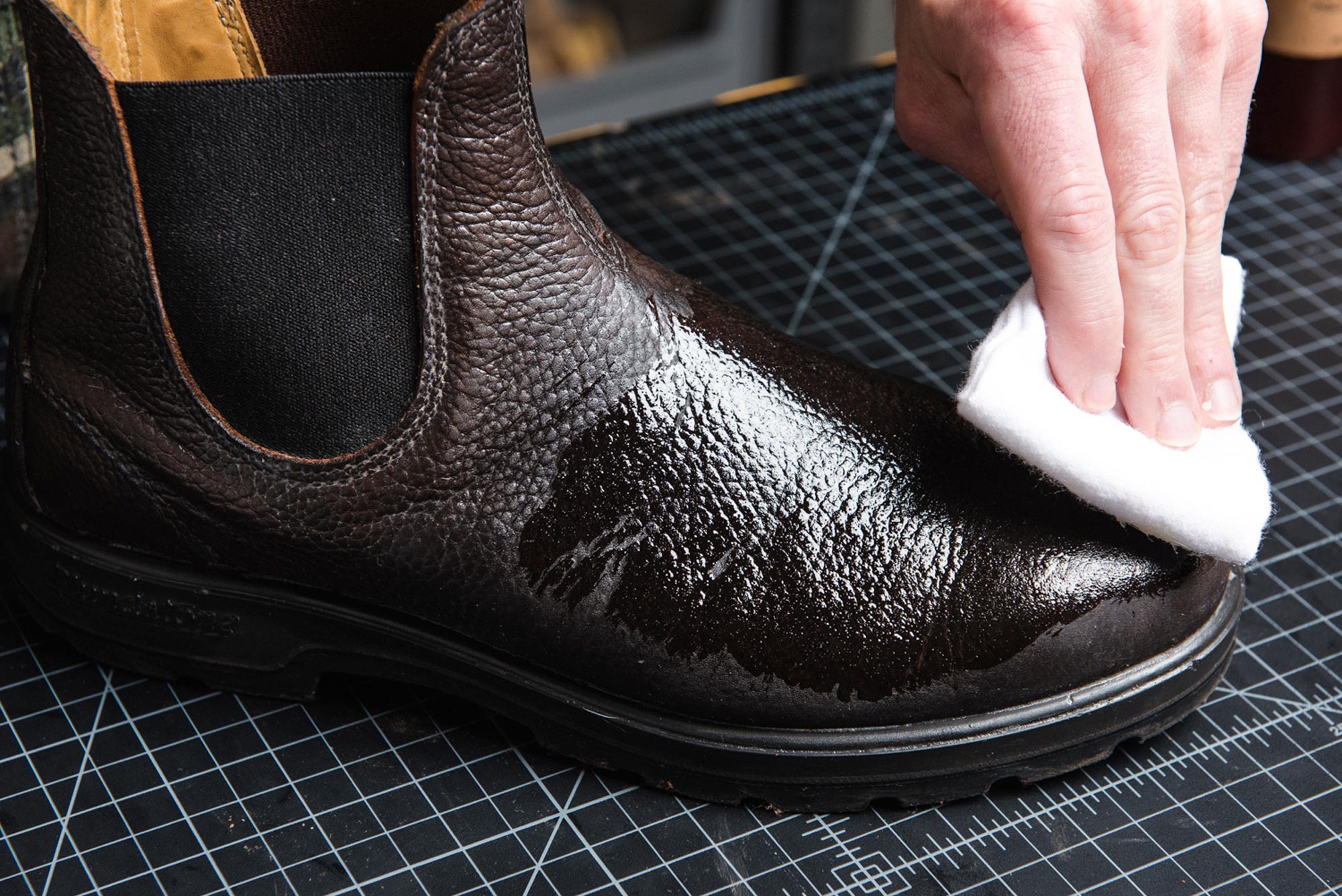 otter wax leather oil being applied to a eather boot