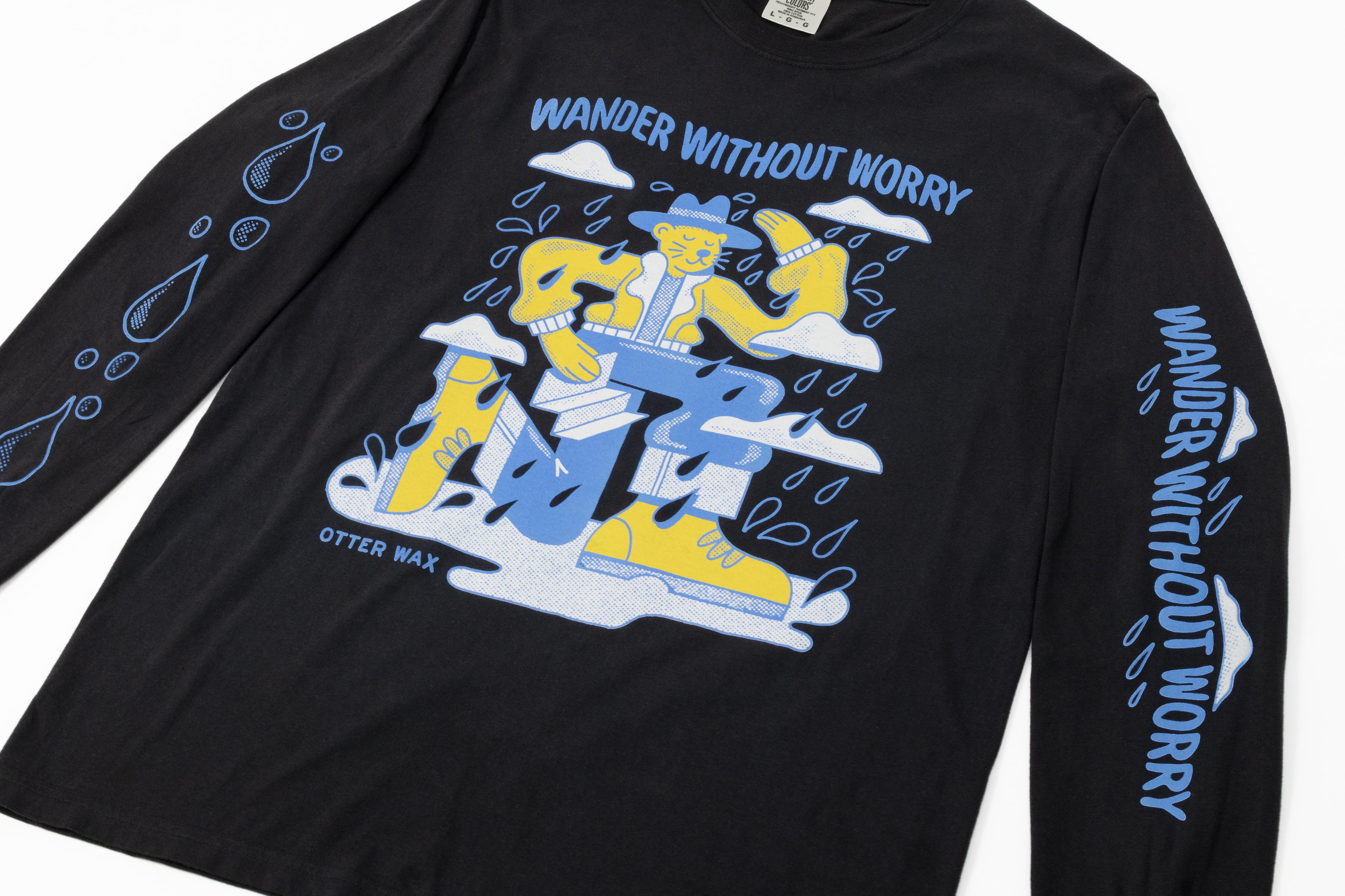 Black Otter Wax long sleeve t-shirt featuring a colorful “Wander Without Worry” graphic of an otter in outdoor gear surrounded by raindrops and clouds.