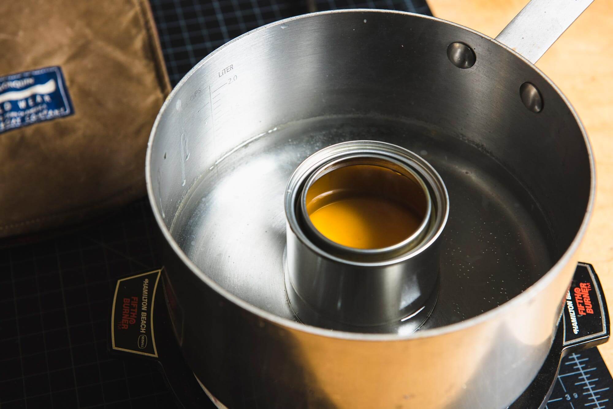 a tin of otter wax fabric dressing melting in a pan of hot water