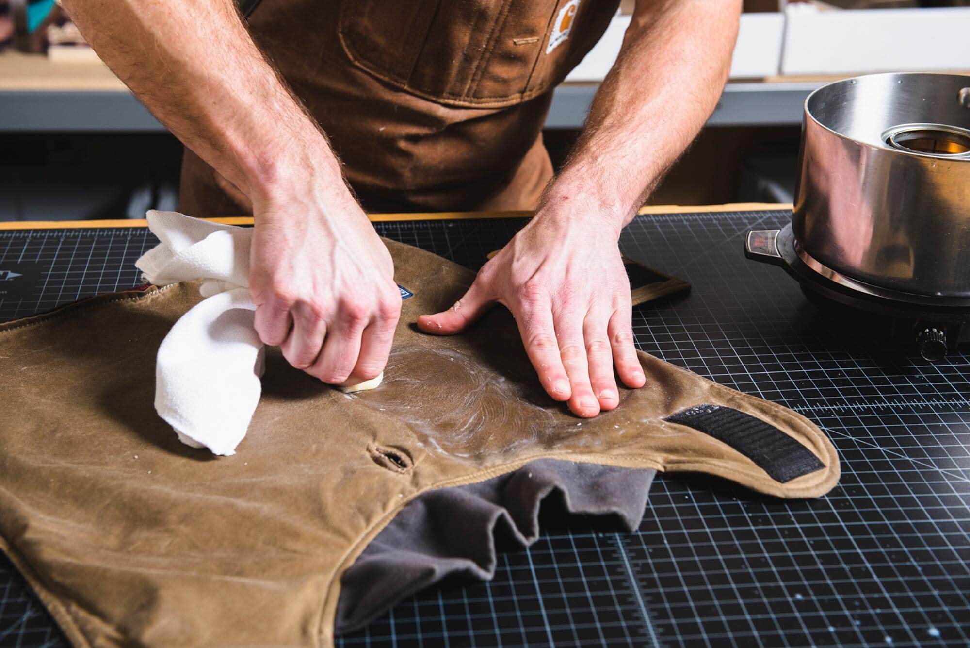 hands rubbing heat activated fabric dressing into canvas for waterproofing